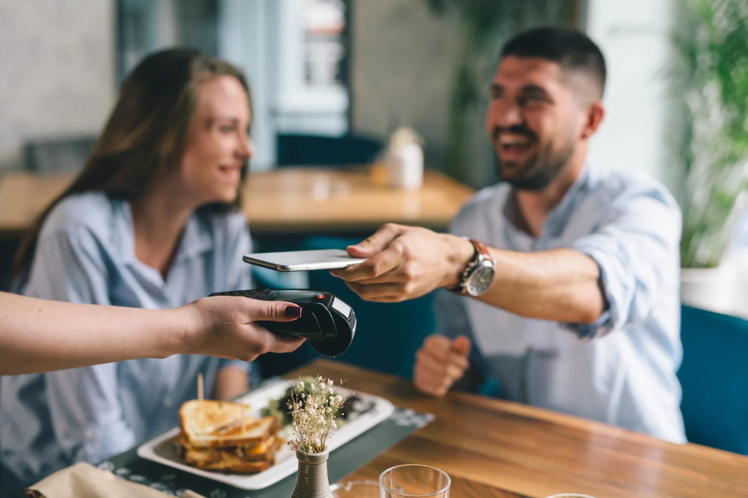 people in cafe using mobile payment terminal